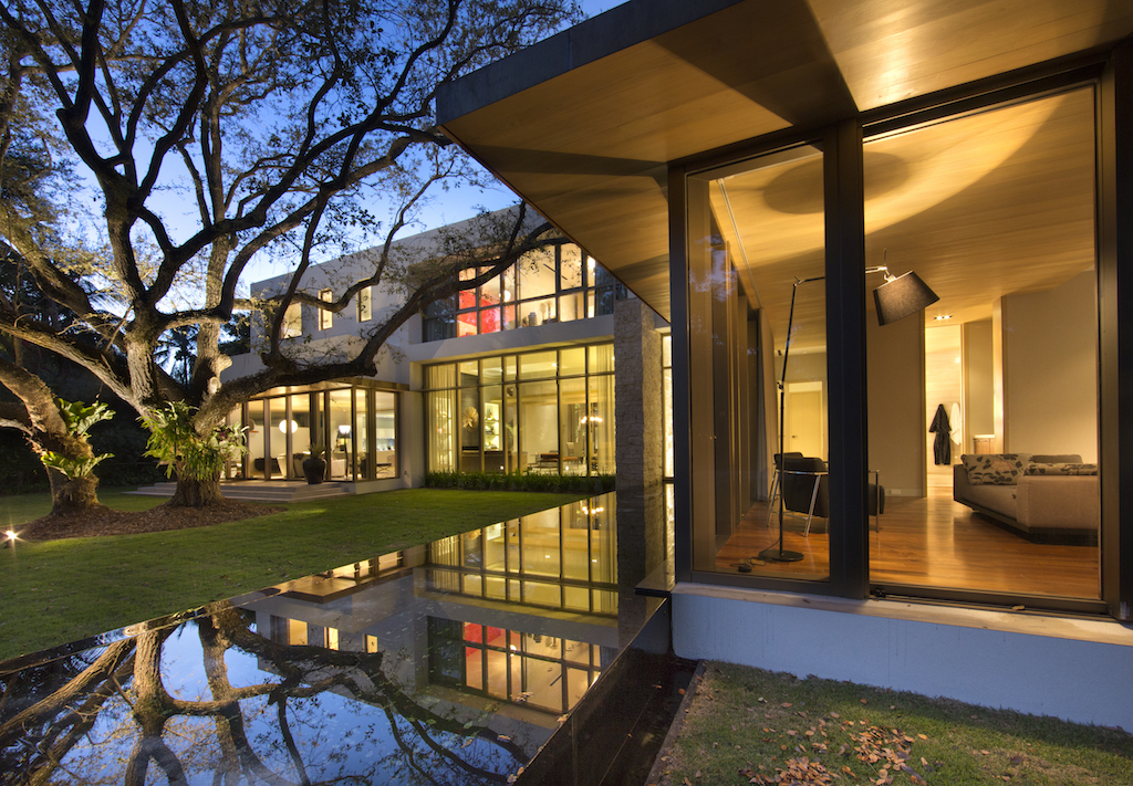 tree in a beautiful garden,modernist glass house,modern living room with view,luxury house lit by night,contemporary architecture florida,